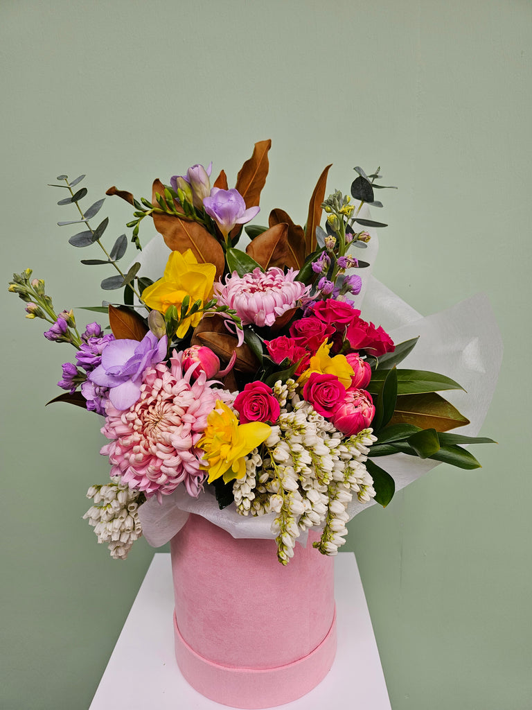 Send someone special this happy, beautiful spring mix made with seasonal spring blooms, displayed in a pink hat box.  Please note flowers will vary to what is pictured due to availability of product, please be reassured that every bouquet will be individually created for you at Pick a posy Studio Lyall Bay Florist  from a selection of seasonal New Zealand market fresh flowers, designed with love and care.